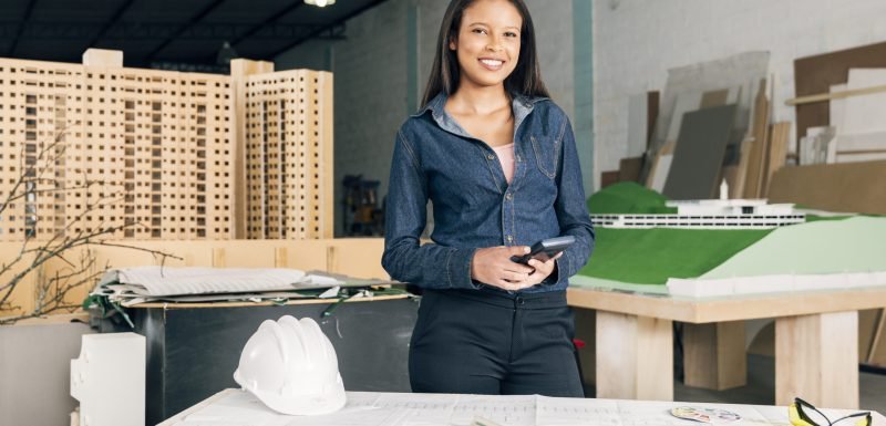 african-american-woman-with-calculator-near-table-with-safety-helmet-equipments