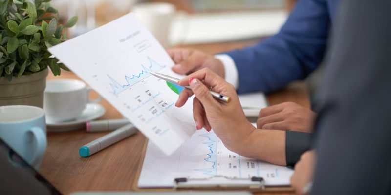 hands-man-woman-business-attire-sitting-desk-office-discussing-graph