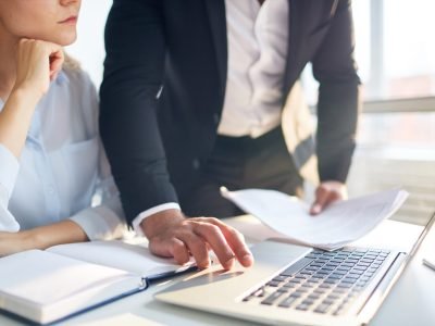 Businessman making online presentation in laptop to his colleague or subordinate by desk