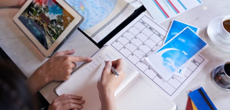 Close-up shot of unrecognizable couple taking necessary notes and planning vacation trip to Europe while sitting at table